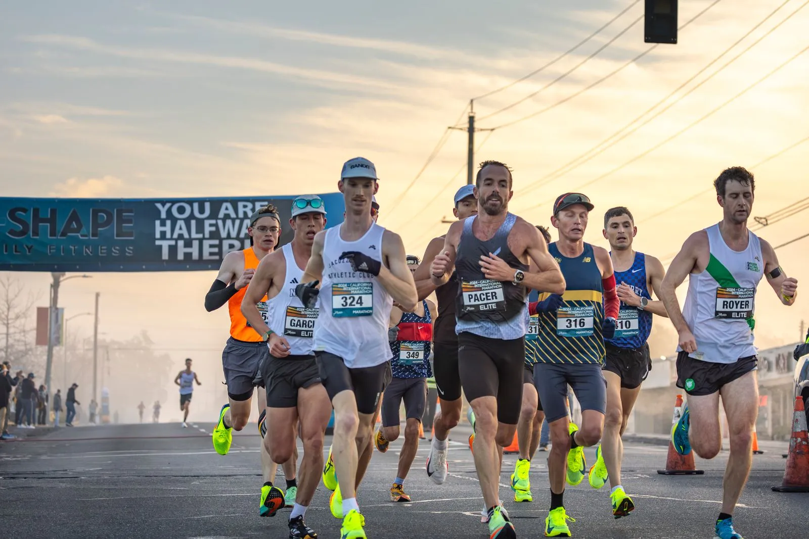 Marathon runners push through a competitive outdoor race, captured at sunrise.